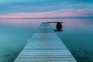 Jetty reaching out in the calm evening ocean at sunset.