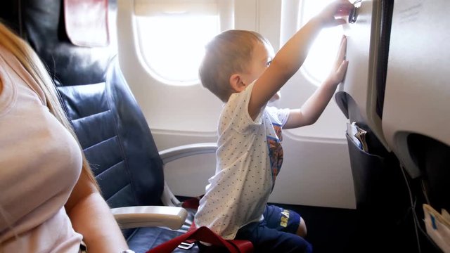 4k footage of adorable smiling toddler boy playing with table on passenger seat at airplane