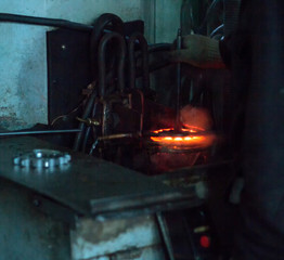 The worker makes hardening heat treatment of the metal gear on a special machine, close-up,...
