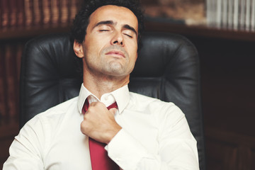 Businessman loosing his necktie after an hard working day