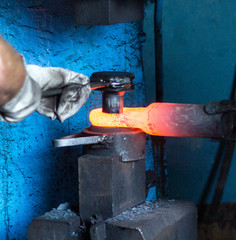 Men make a metal red-hot detail in an old smithy, close-up, red-hot meta, forging