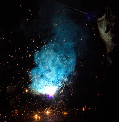 welder welds metal parts, many sparks and fumes, welding, welding arc, bright flash, close-up