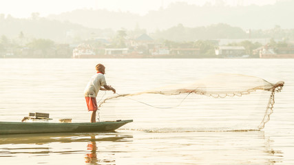 traditional fisherman in Mahakam river, Samarinda, Indonesia, catching fish using net in the morning