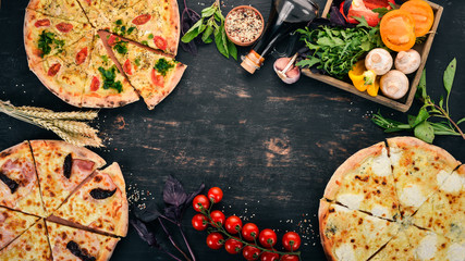 A set of pizza. On a black wooden background. Free space for text. Top view.