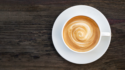 Naklejki  Gorąca kawa cappuccino latte spiralna pianka widok z góry na ciemnym drewnianym tle