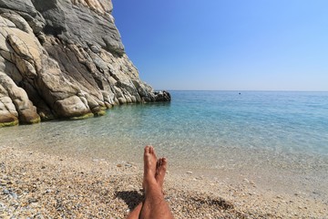relaxing on a lonesome tropical beach with pebble stones and azure blue water