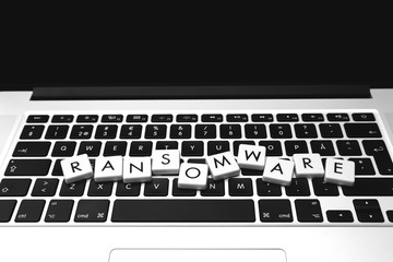 Ransomware text on top of a modern laptop. Image in black and white.
