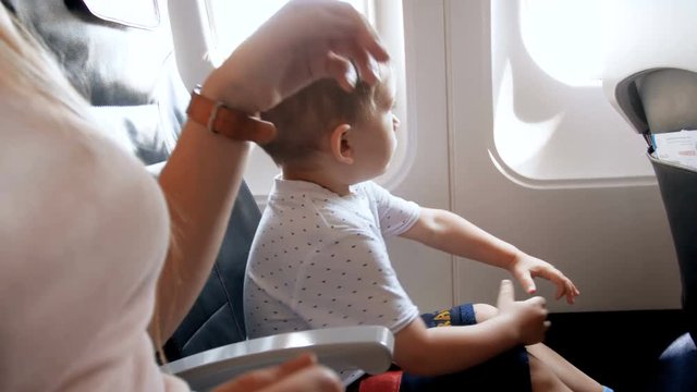 4k video of young mother holding her toddler son by hand during take off in airplane