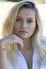 Young blonde teenager with blue eyes on a bench 