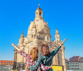 Two happy women hugging and looking at the main attraction of Dresden - Frauenkirche . The concept...