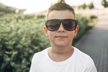 Portrait of a Little Boy in Black Sunglasses and White T-Shirt Outdoors