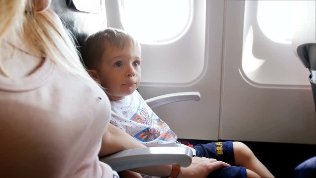 4k footage of little toddler boy nervously looking at mother during airplane taking off the ground