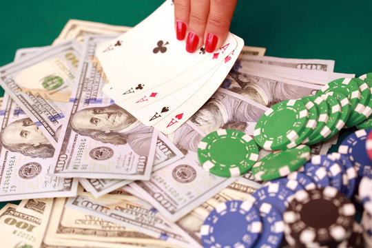 Woman playing poker with cards, chips and cash on the green casino table