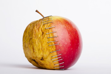 Fresh red and old yellow apple halves with staples on white background, plastic surgery  metaphor - 222667094