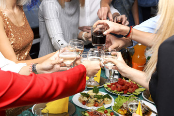 Friends clink glasses over the festive table at a party
