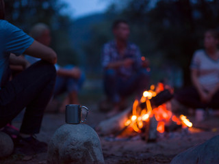 young friends relaxing around campfire