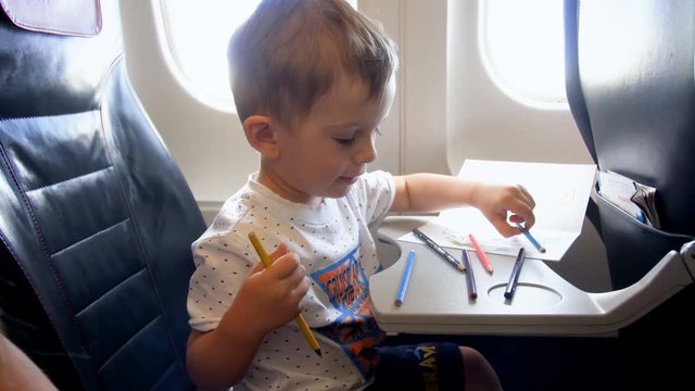 4k video of little toddler boy drawing with pencils during long flight in airplane