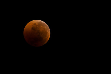 bloody moon close-up against a black sky as a result of an astronomical event lunar eclipse. View in telescope, placement on the side for additional text
