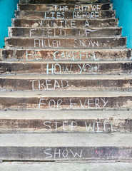 Inspirational message written on the footsteps of an old stone staircase