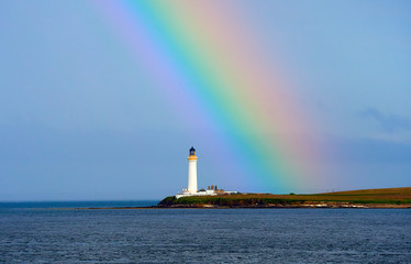 High lighthouse with rainbow running along its top, Orkney Islands, Scotland