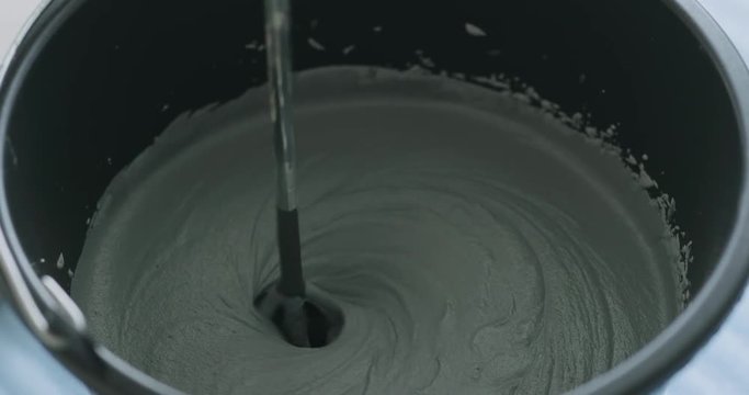 Slow motion closeup mixing dark gray micro concrete plaster