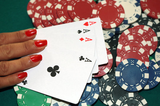 Woman playing poker with four of aces and chips 