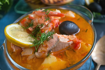 French fish soup Bouillabaisse with seafood, salmon fillet, shrimp, rich flavor, delicious dinner in a white beautiful plate.