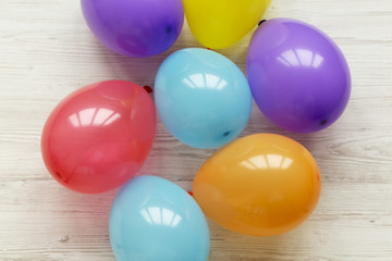 Colorful balloons on white wooden background. Decoration party concept, top view. Flat lay.