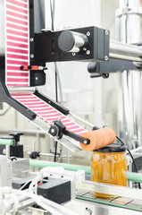 Vertical image of packing honey jars in factory.