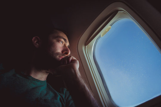 Pensive man looking outside through the window of an airplane