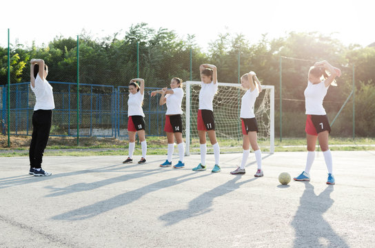 Young female handball players stretching