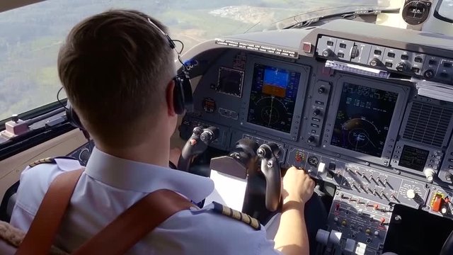 Professional pilot controlling indicators on the control panel while plane of autopilot.