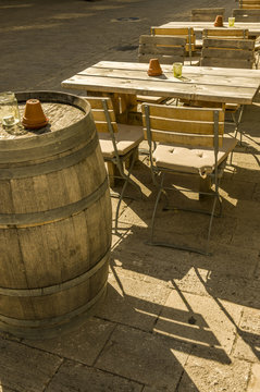 Aussenbestuhlung eines Weinlokals mit Tischen St&uuml;hlen und F&auml;ssern als Stehtische im Sonnenschein, Outside seating of a wine bar with tables chairs and barrels as bar tables in the sunshine