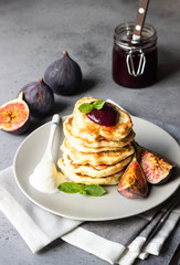 Homemade fluffy pancake with fig jam and fruits decorated with mint and natural yogurt in spoon
