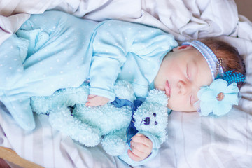 Sleeping newborn baby with a teddy bear