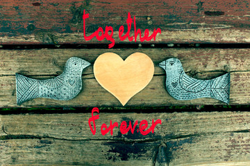 love card / two wooden birds and heart made of seeds on the wooden background with inscription love you 
