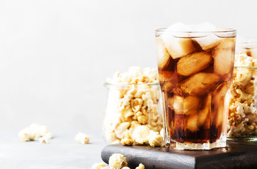 Sweet soda with ice cubes and caramel popcorn, gray background, selective focus