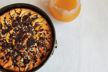 apple pie in the baking form and a jar with juice