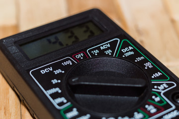 Digital measuring multimeter on wooden floor. It shows 4.33V or fully charged battery. Includes...