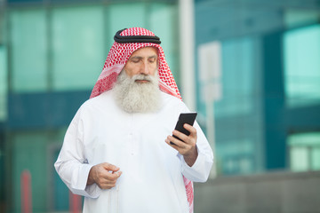 Arab businessman working with his phone on a street in the background