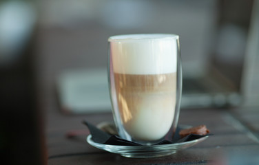 Hot art Latte Coffee in a cup on wooden table and and laptop in coffee shop blur background with bokeh image.