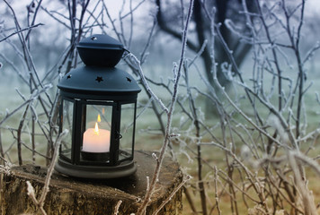 burning lantern in the misty frozen garden 