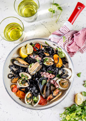 Homemade seafood Black pasta spaghetti with clams mussels octopus vongole in pan with white wine on marbled background