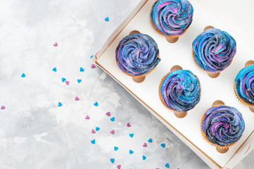 Box with cupcakes with dark whipped cream on grey background