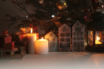 A New Year and Christmas background with decorated Tree, wooden toy houses, toy deer,wooden bird ,toy sledge,lantern, candles, gifts with ribbons