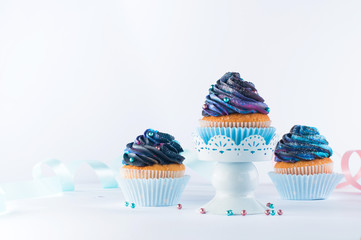 Galaxy cupcakes with colorful whipped cream on light party background