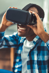 Virtual world. Exuberant afro american man putting on VR glasses and touching them