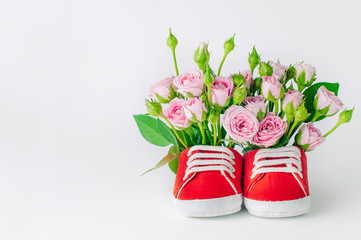 Red baby shoes with rose flowers over light background