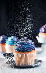 Vanilla cupcake sprinkled with sugar powder on black background