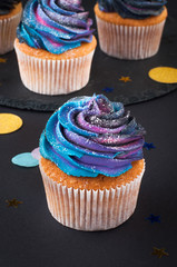 Vanilla cupcakes with dark whipped cream on black background